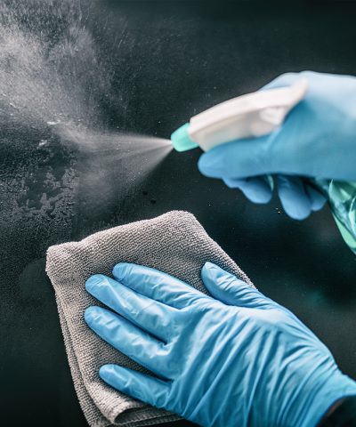 Person rengör yta med sprayflaska och trasa